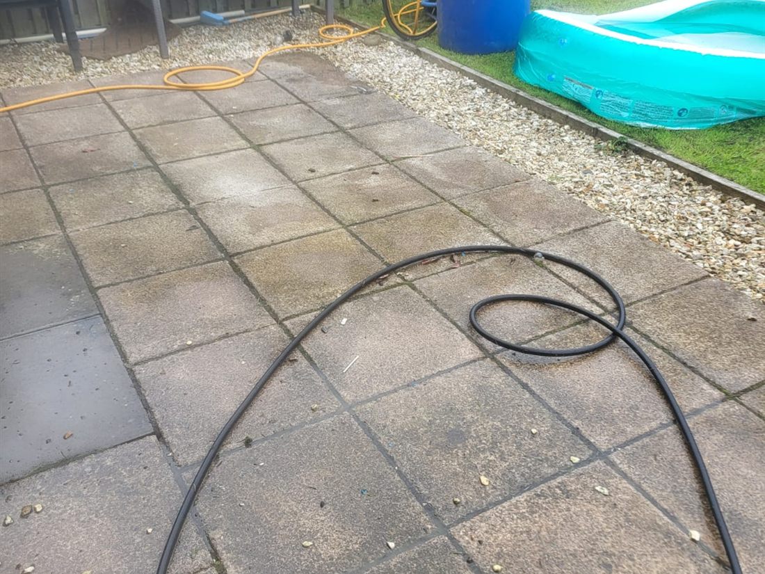 Patio slabs before pressure washing with grime and debris visible